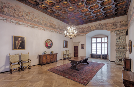 Sala w zamku z drewnianą podłogą, obrazami oraz freskami na ścianach