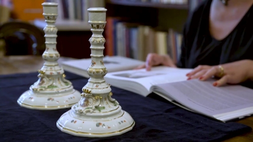 para porcelanowych świeczników, w tle rozłożone ręce na książce