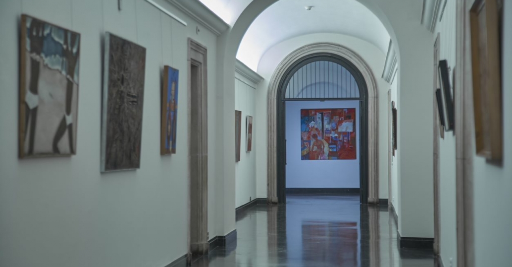 oświetlony korytarz w starym budynku, na ścianach zabytkowe obrazy