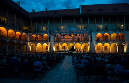 nocny widok dziedzińca arkadowego na Wawelu, nastrojowe światło, publiczność ogląda występ muzyczny