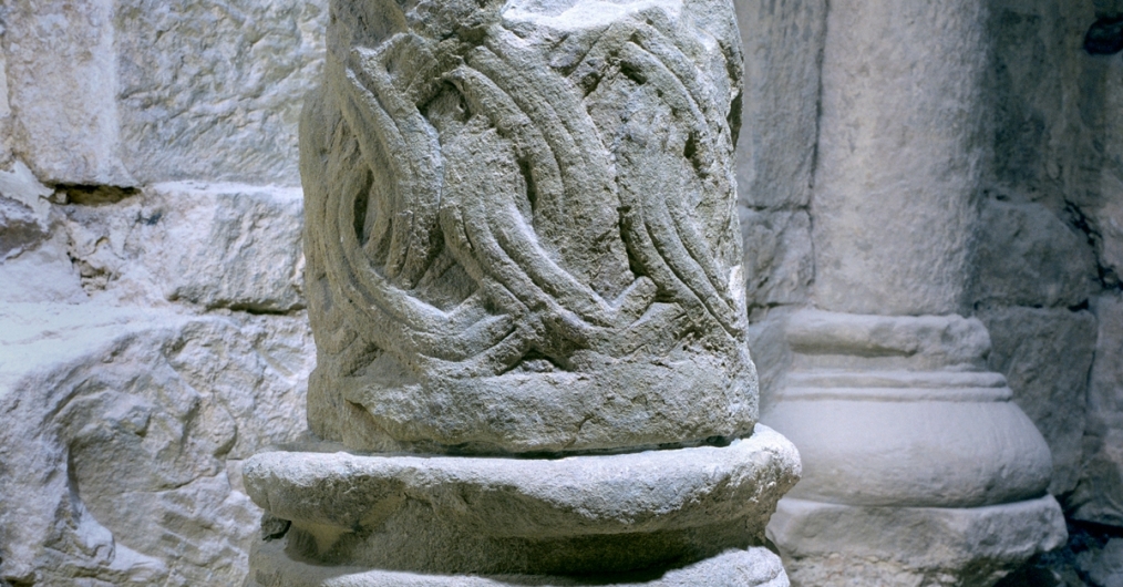 fragment zabytkowej romańskiej kamiennej kolumny, obła podstawa, trzon zdobiony motywem plecionki