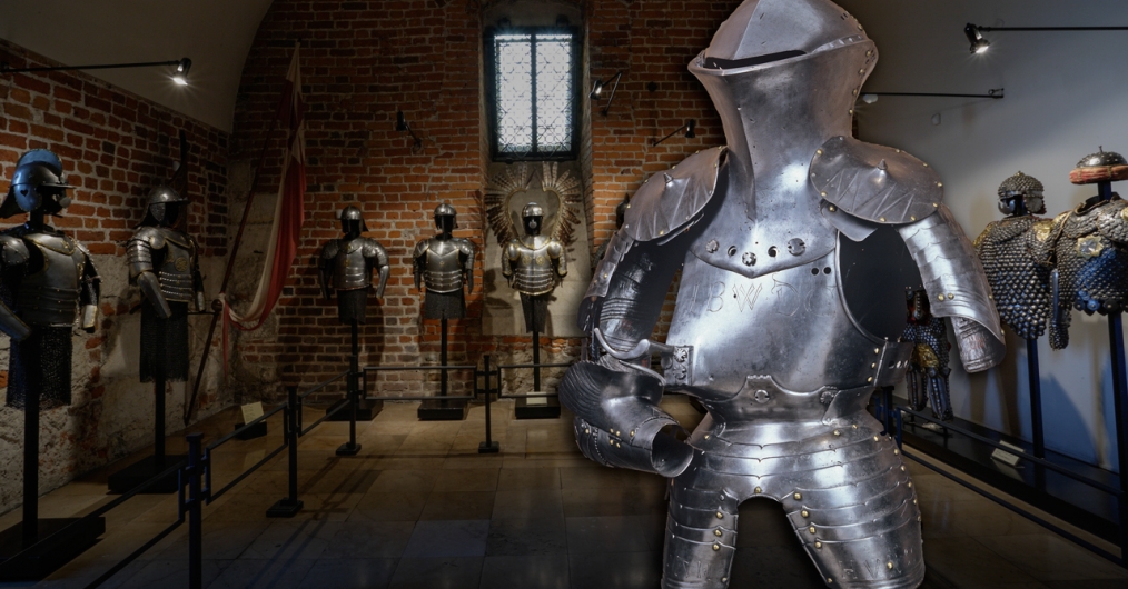 późnośredniowieczna zbroja turniejowa na tle ekspozycji zbroi w jednym z pomieszczeń Skarbca Koronnego i Zbrojowni Zamku Królewskiego na Wawelu