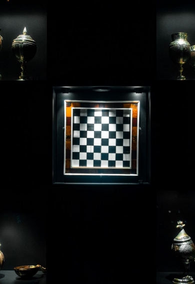 Kunstkamera z planszą szachową w centrum i kielichami po bokach.
