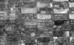widok zniszczonego muru ceglanego, z wmontowanymi płytkami kamienia - cegiełkami wawelskimi