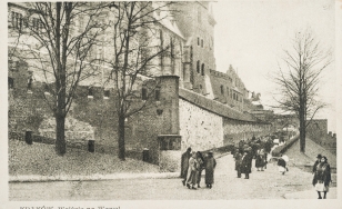 Stara pocztówka z drogą na Wawel, na tle muru z cegiełkami postacie ludzi
