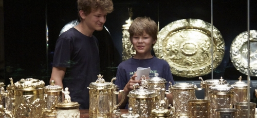 dwóch chłopców przygląda się cennym złotym naczyniom ustawionym w gablocie muzealnej