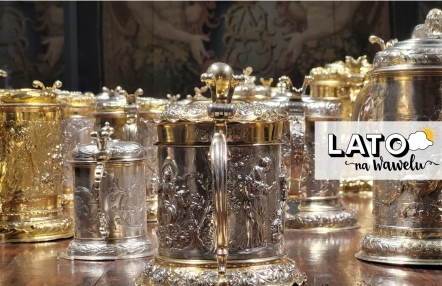 złote i srebrne kubki i kufle, zdobione puncowanymi motywami figuralnymi, w tle fragment arrasu z monogramem króla Zygmunta Augusta (SA)