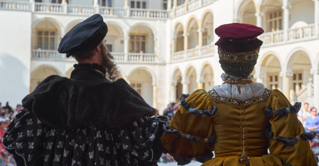 kobieta i mężczyzna w renesansowych strojach, stoją tyłem do widza, na tle dziedzińca zamkowego