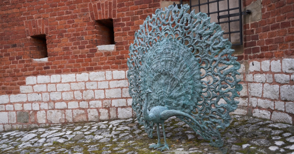 Rzeźba pawia na tle murów, przy wejściu do ogrodów królewskich