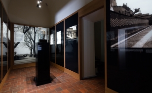 Wystawa Wawel Odzyskany, korytarz ze zdjęciami na ścianach, pośrodku popiersie na postumencie
