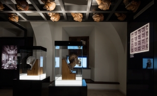 Wystawa Wawel Odzyskany, w gablotach i pod sufitem drewniane rzeźby - kopie głów wawelskich