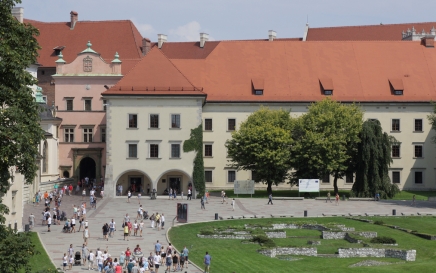 widok fragmentu dziedzińca na Wawelu, trawniki i budynki, przechadzający sie ludzie