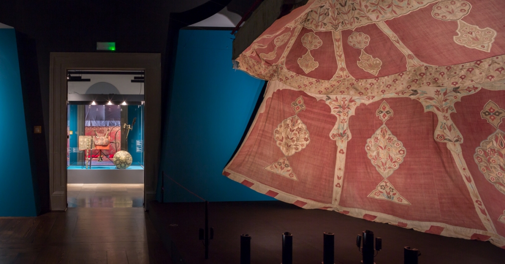 sala wystawy z namiotami tureckimi, w nastrojowo oświetlonym wnętrzu rozmieszczone obiekty muzealne: namioty, broń, elementy uzbrojenia
