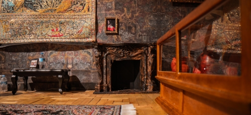 sala wystawy w zamku, na ścianach barwne tapety, obiekty rozstawione na zabytkowych meblach