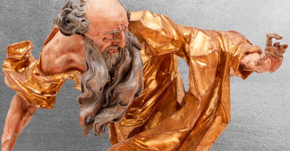 fragment rokowej drewnianej rzeźby; postać mężczyzny widoczna z boku, długie siwe rozwiane włosy, ekspresyjnie rzeźbiona złocona szata