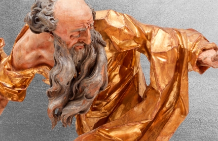 fragment rokowej drewnianej rzeźby; postać mężczyzny widoczna z boku, długie siwe rozwiane włosy, ekspresyjnie rzeźbiona złocona szata