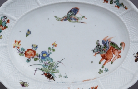 Na zdjęciu widoczny jest owalny talerz - patera. Wykonany jest z białej ceramiki i ozdobiony kolorowymi motywami kwiatowymi oraz fantazyjnymi przedstawieniami zwierząt.