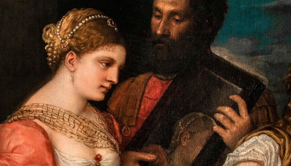 fragment obrazu, przedstawia młodą kobietę, w czerwono-białej sukni, włosy spięte sznurem pereł, z tyłu mężczyzna trzyma lustro, w którym odbija się jej twarz