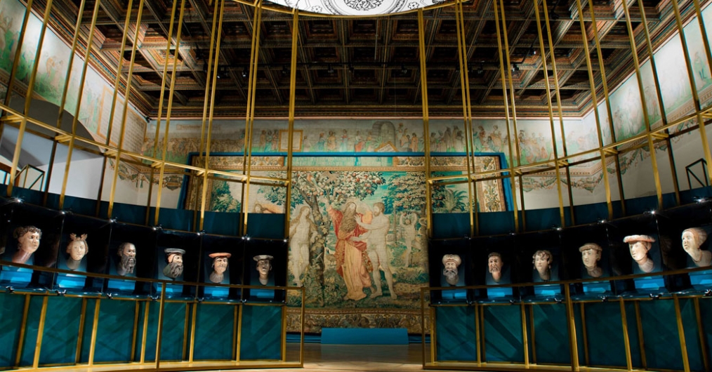Wnętrze sali wypełnia półkolista konstrukcja złotych stelaży, pozwalająca stanąć z wawelskimi głowami „twarzą w twarz”. W tle ukazany jest arras z biblijną sceną „ Szczęśliwość rajska”.