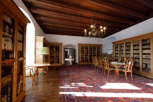 Wnętrze jednego z pomieszczeń na Zamku Pieskowa Skała z pięcioma szafami zastawionymi książkami oraz podłużnym stołem przy jednej z dłuższych ścian.