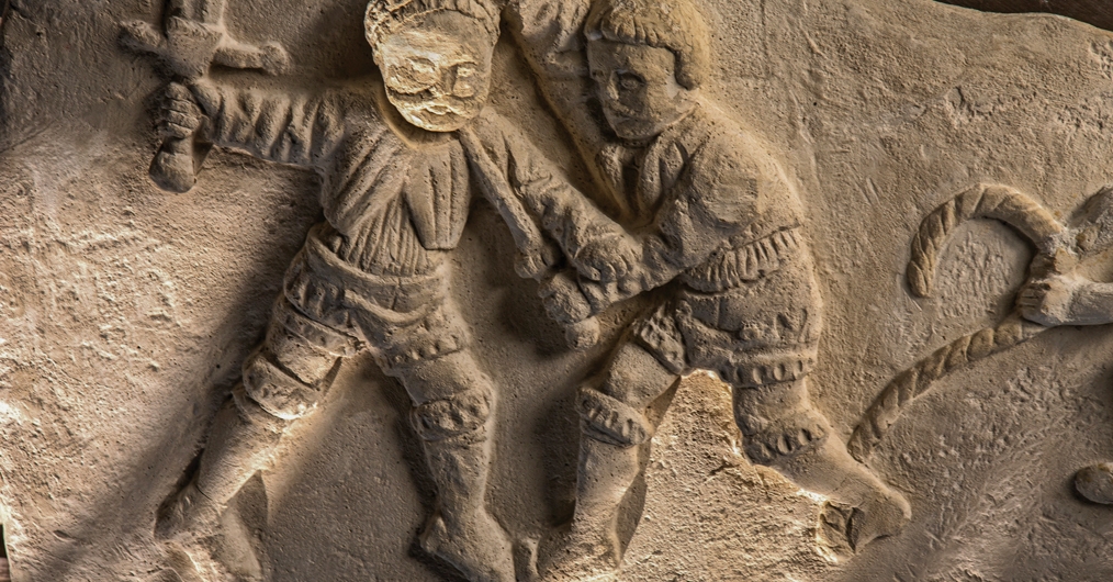 Fragment kaminnej płaskorzeźby przedstawiającej dwie walczące ze sobą męskie postacie
