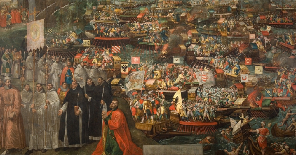 obraz przedstawiający scenę bitwy; w tle flota okrętów pełnych postaci walczących żołnierzy, po lewej stronie procesja mnichów niosących sztandar z Matką Boską, na pierwszym planie klęczący mężczyzna w czerwonej szacie