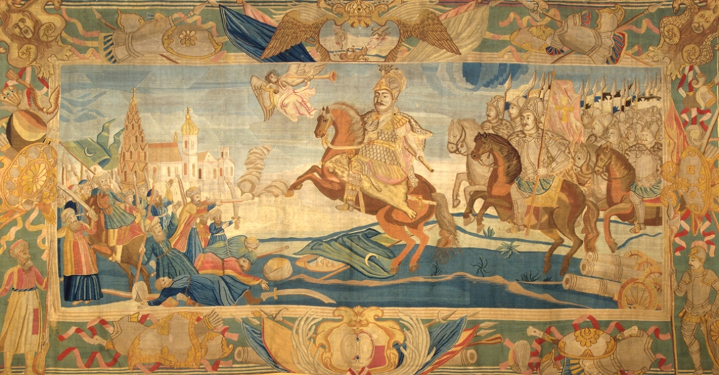 barwna tkanina, w centrum postać jeźdźca na koniu, za nim wojsko na koniach; z lewej strony miasto; dookoła ornamenty roślinne