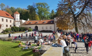 Zdjęcie przedstawia uczestników wydarzenia podczas tworzenia prac plastycznych w ogrodzie na dziedzińcu.