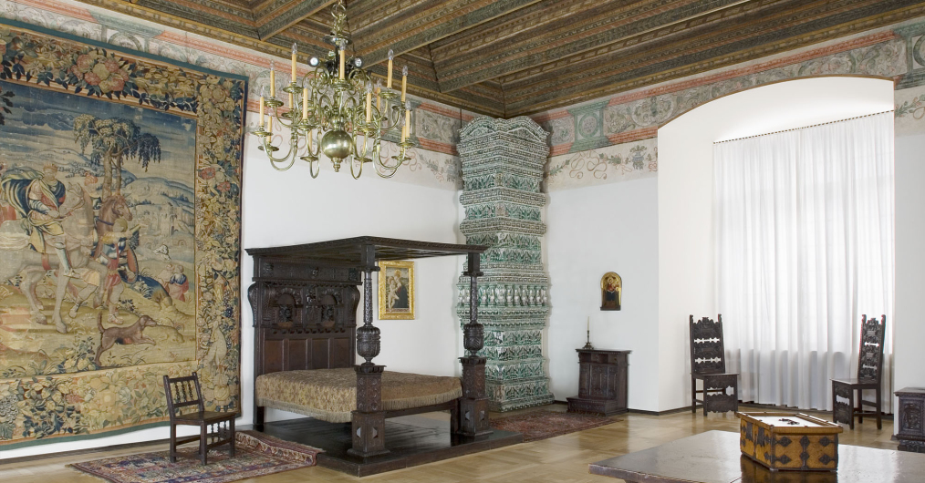 sala muzealna w zamku, na ścianie arras, w rogu łóże z baldachimem