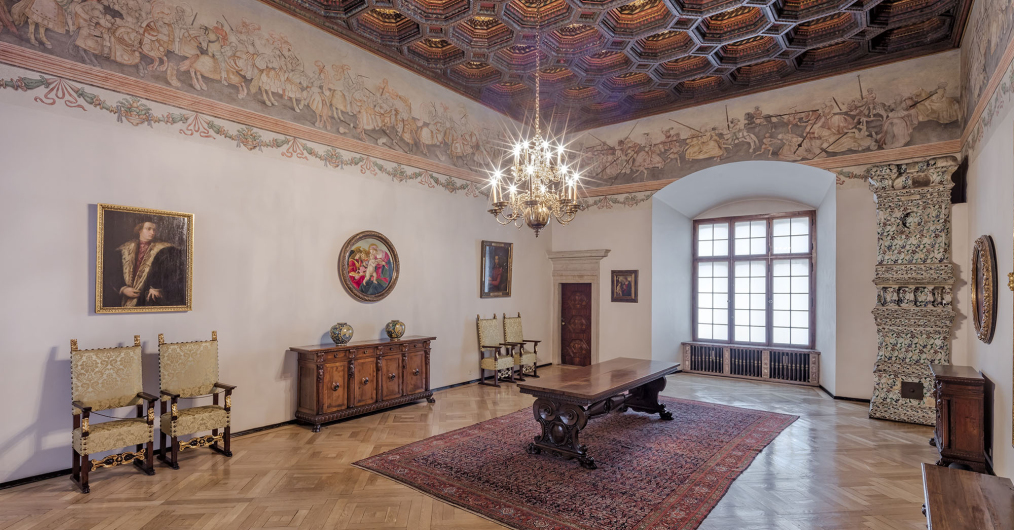 Sala w zamku z drewnianą podłogą, obrazami oraz freskami na ścianach