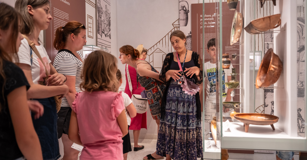Grupa ludzi ogląda ekspozycję miedzianych garnków w muzeum