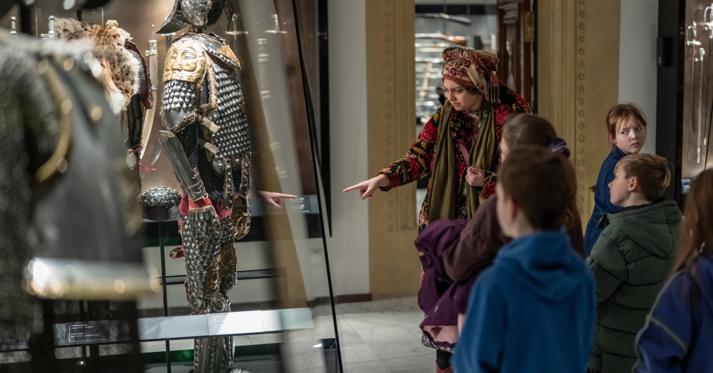 Zafascynowane dzieci przyglądają się zbrojom na wystawie, ucząc się o dawnych czasach i rycerzach.