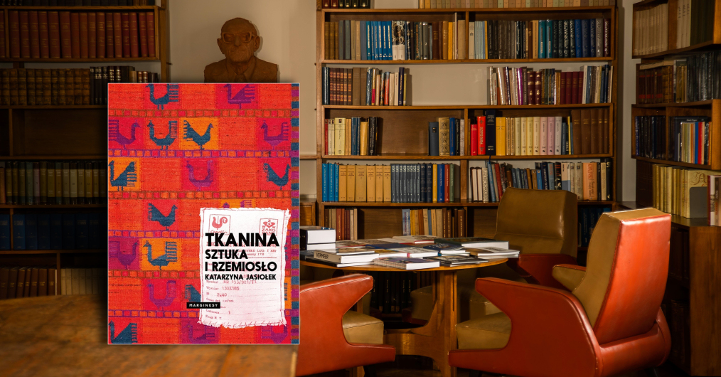 wnętrze biblioteki, na stole książka z widoczną okładką