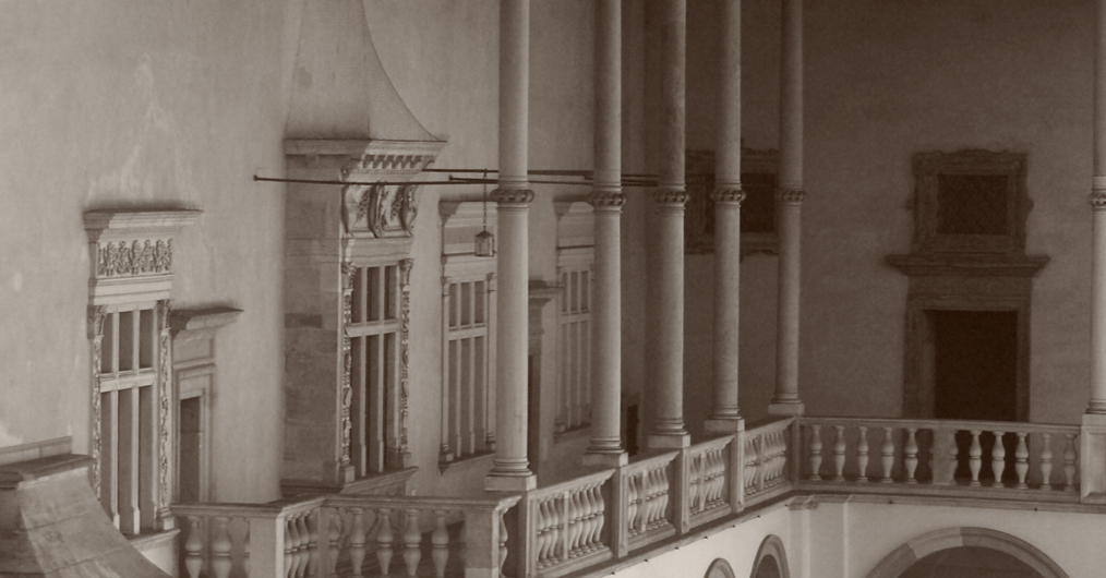 Fotografia w sepii przedstawiająca fragment zamkowych krużganków.