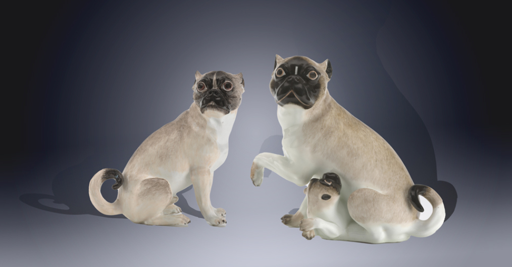 porcelanowe figurki dwóch mopsów, przy piesku z lewej strony leżący szczeniak