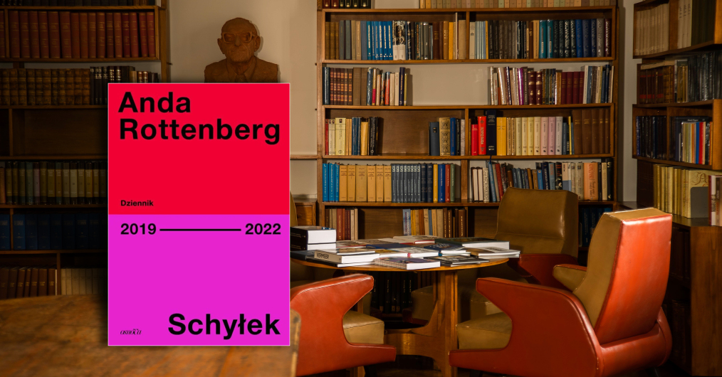 wnętrze biblioteki, na stole książka z widoczną okładką