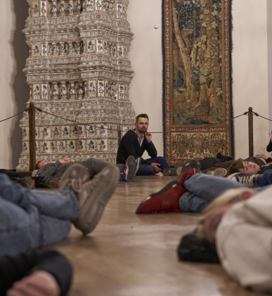 Grupa ludzi leży na podłodze, relaksując się i rozmawiając ze sobą w przyjaznej atmosferze.