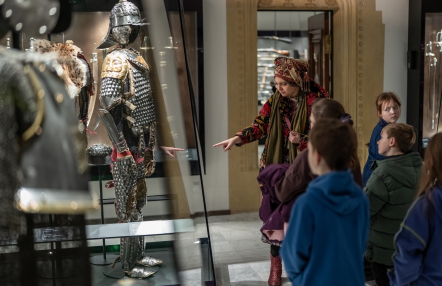 Zafascynowane dzieci przyglądają się zbrojom na wystawie, ucząc się o dawnych czasach i rycerzach.