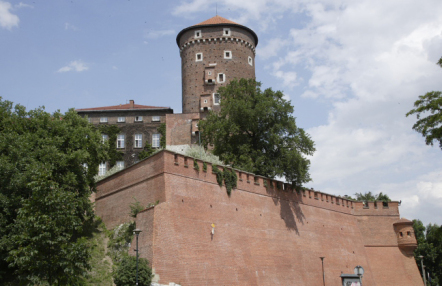 widok murów otaczających Wawel, ponad muram okrągła ceglana baszta, nakryta spadzistym dachem