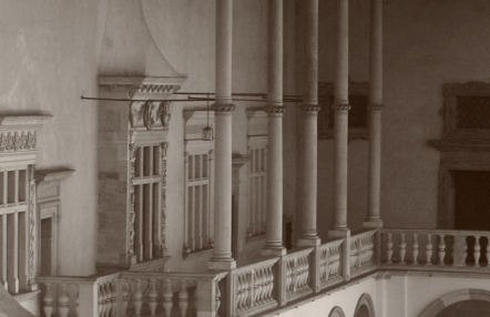 Fotografia w sepii przedstawiająca fragment zamkowych krużganków.