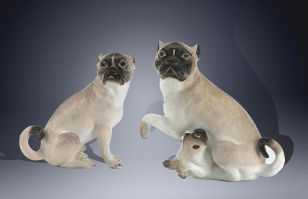 porcelanowe figurki dwóch mopsów, przy piesku z lewej strony leżący szczeniak