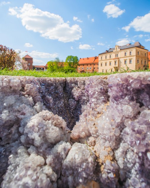 Ametystowe kryształy w glebie, widok na budynek w tle.