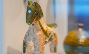 Ceramiczna figurka konia, kolorowana, z detalami podkreślającymi jego kształt i teksturę.