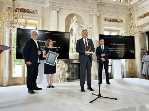 grupa odświętnie ubranych osób stojących na scenie