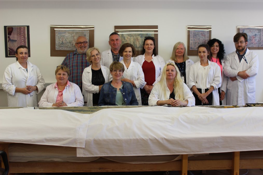 grupa osób w pracowni konserwacji zabytków archeologicznych, na stole pudełak z obiektami zabytkowymi