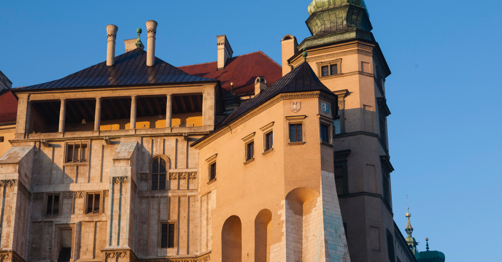 Duży budynek z wieżą zegarową, dominujący w krajobrazie, z wyraźnymi detalami architektonicznymi.