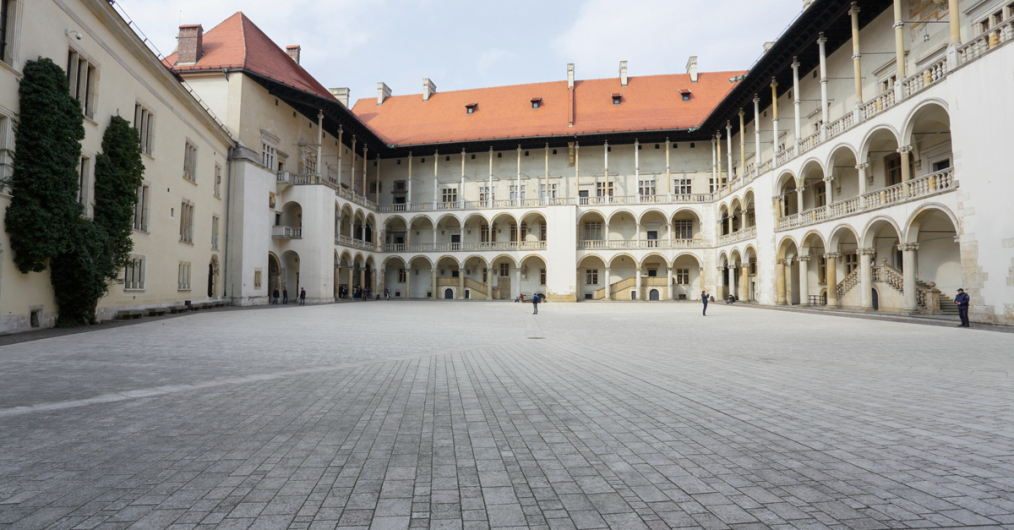 Wielki dziedziniec zamkowy, pokryty kamienną kostką, otoczony z trzech stron budynkami, każde piętro posiada bogato zdobione krużganki, czyli rodzaj balkonu, na budynku z lewej strony winorośl