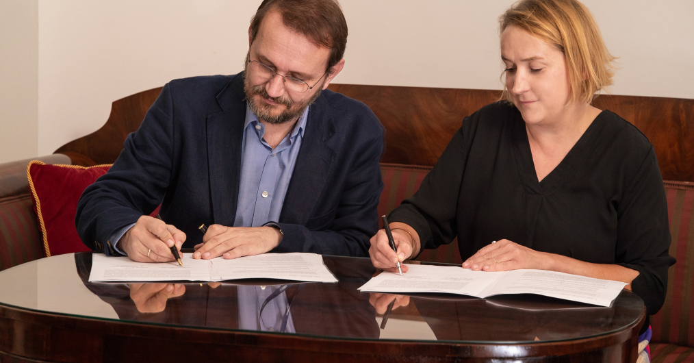 mężczyzna i kobieta siedzą przy stole, podpisują dokumanty